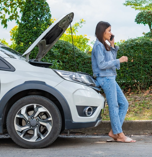 Woman on phone next to broken car